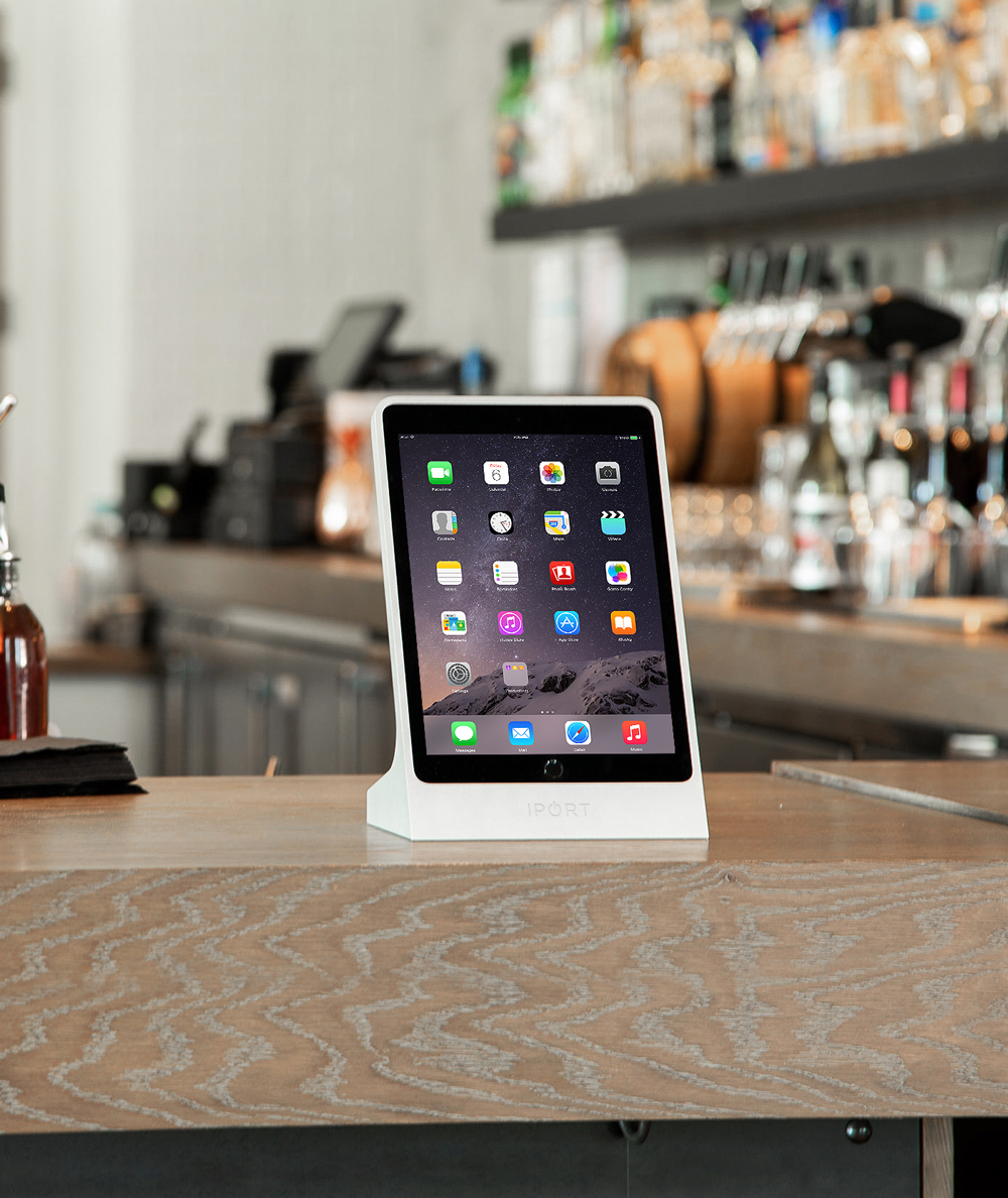 Silver iPad stand by IPORT being used on a restaurant bar.